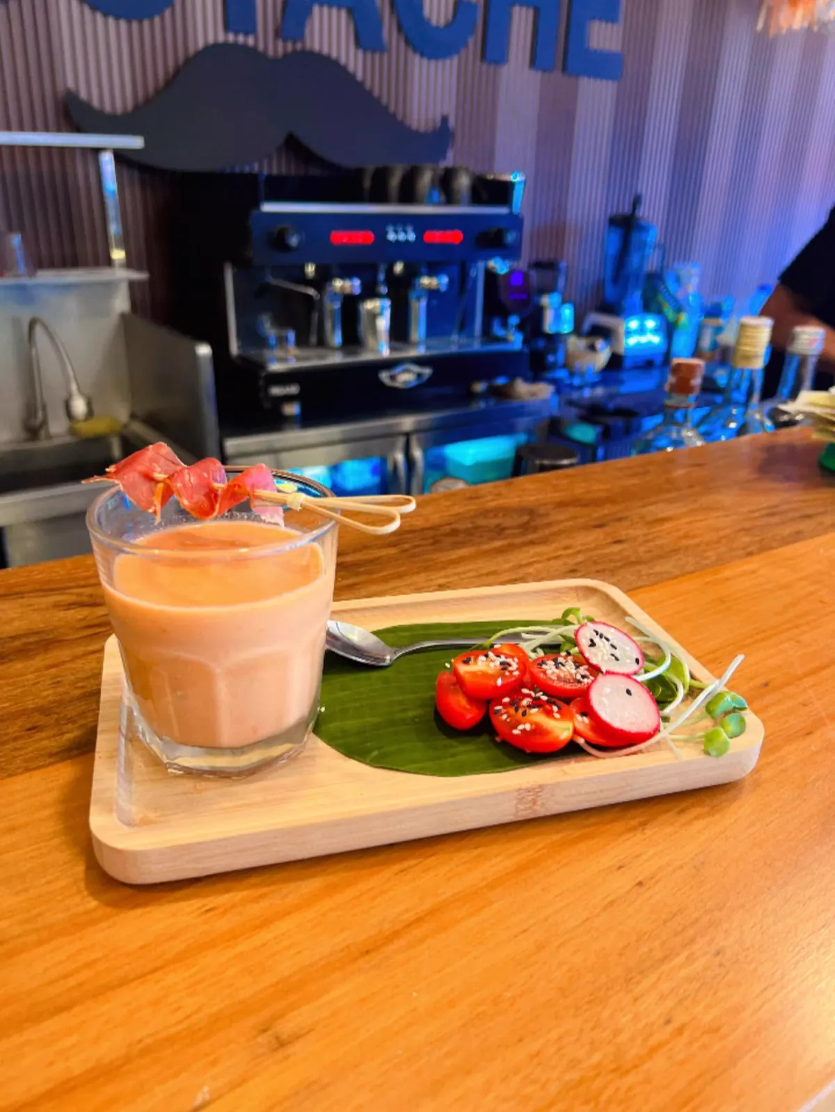 Chilled gazpacho with a ham skewer and tomato-radish salad on a wooden tray