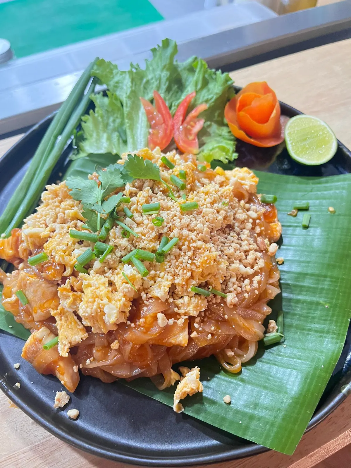 Pad Thai on banana leaf with crushed peanuts, egg, spring onion and lime